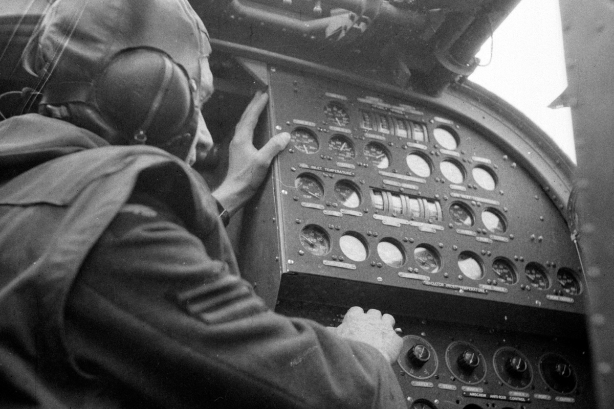 A Flight Engineer seated at his panel inside a Halifax bomber