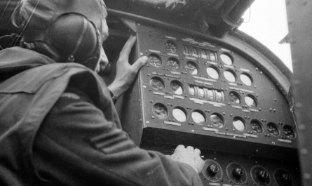 A Flight Engineer seated at his panel inside a Halifax bomber